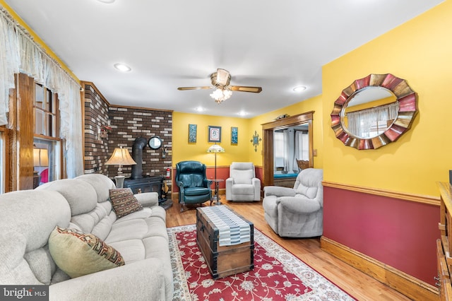 living room featuring ceiling fan, hardwood / wood-style flooring, and a wood stove