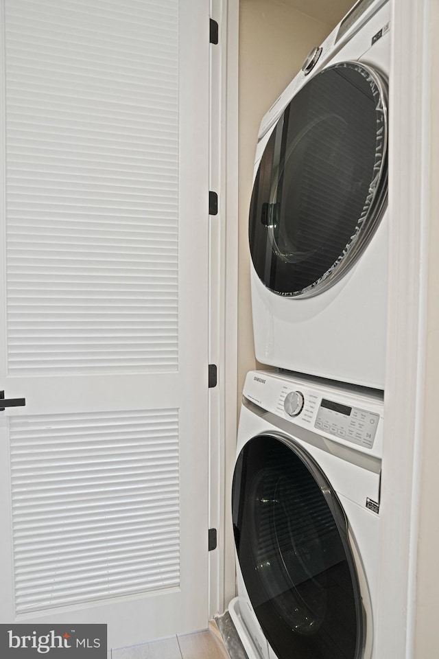 washroom featuring stacked washer / drying machine and light tile patterned flooring