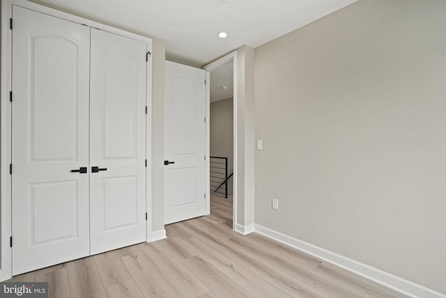 unfurnished bedroom with light wood-type flooring and a closet