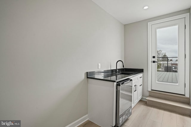 kitchen featuring dishwasher, white cabinetry, sink, and light hardwood / wood-style flooring