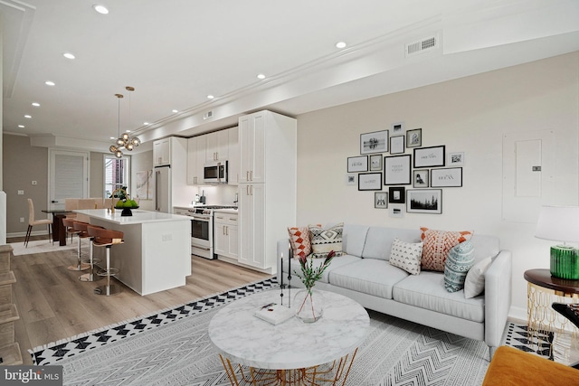 living room with light wood-type flooring, electric panel, and an inviting chandelier