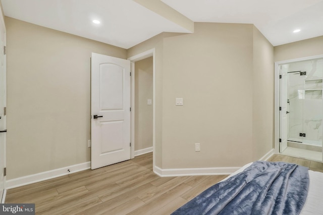 bedroom with ensuite bath and light hardwood / wood-style flooring