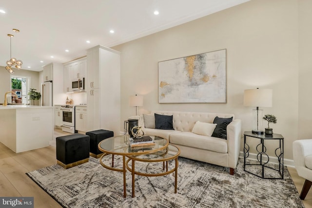 living room with a notable chandelier, light wood-type flooring, and sink