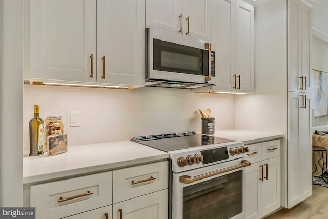 kitchen with light wood-type flooring, stainless steel appliances, white cabinetry, and light stone counters