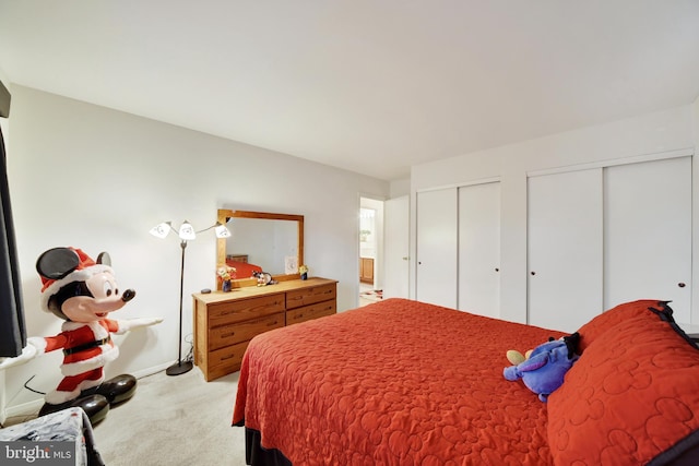 bedroom featuring multiple closets and light carpet