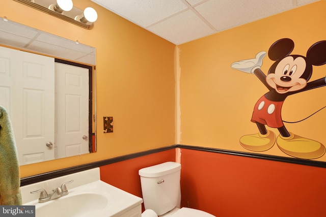 bathroom with toilet, a drop ceiling, and sink