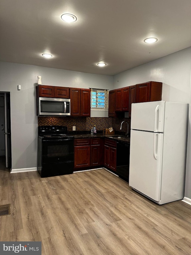 kitchen with decorative backsplash, black appliances, sink, and light wood-type flooring