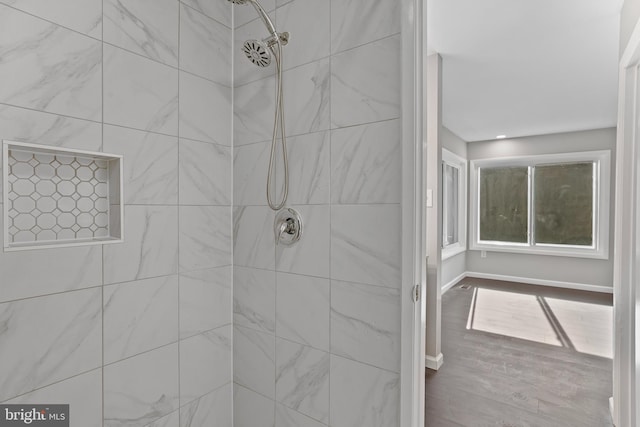 bathroom with a tile shower and wood-type flooring