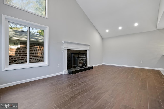 unfurnished living room with dark hardwood / wood-style floors, high vaulted ceiling, and a wood stove