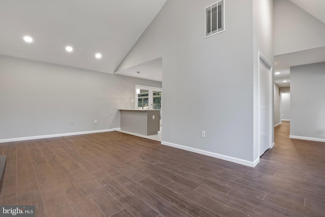 unfurnished living room featuring high vaulted ceiling and dark hardwood / wood-style floors