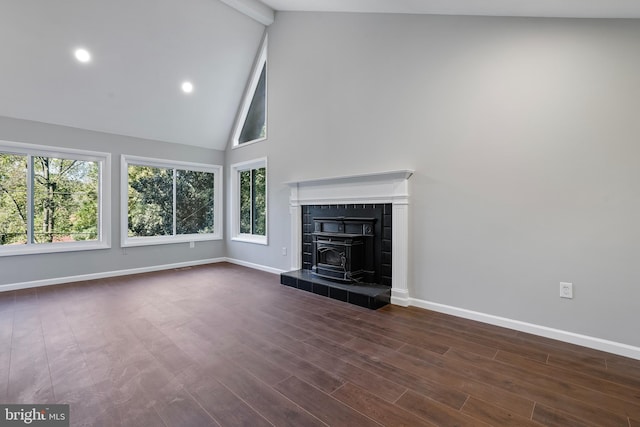 unfurnished living room featuring a wood stove, dark hardwood / wood-style floors, beam ceiling, and high vaulted ceiling