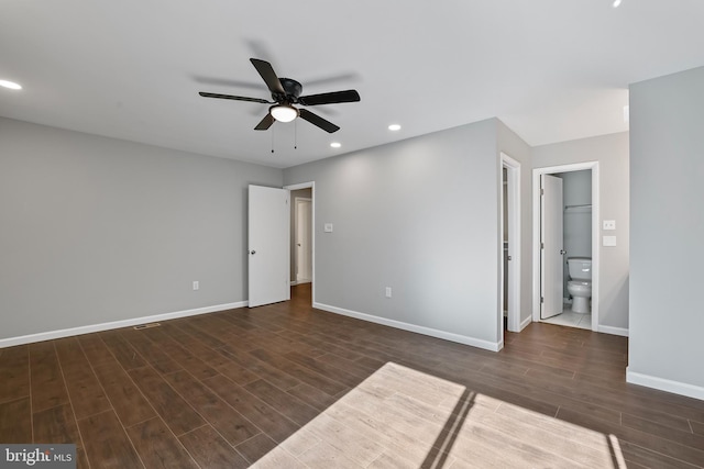 unfurnished bedroom featuring connected bathroom, dark wood-type flooring, and ceiling fan