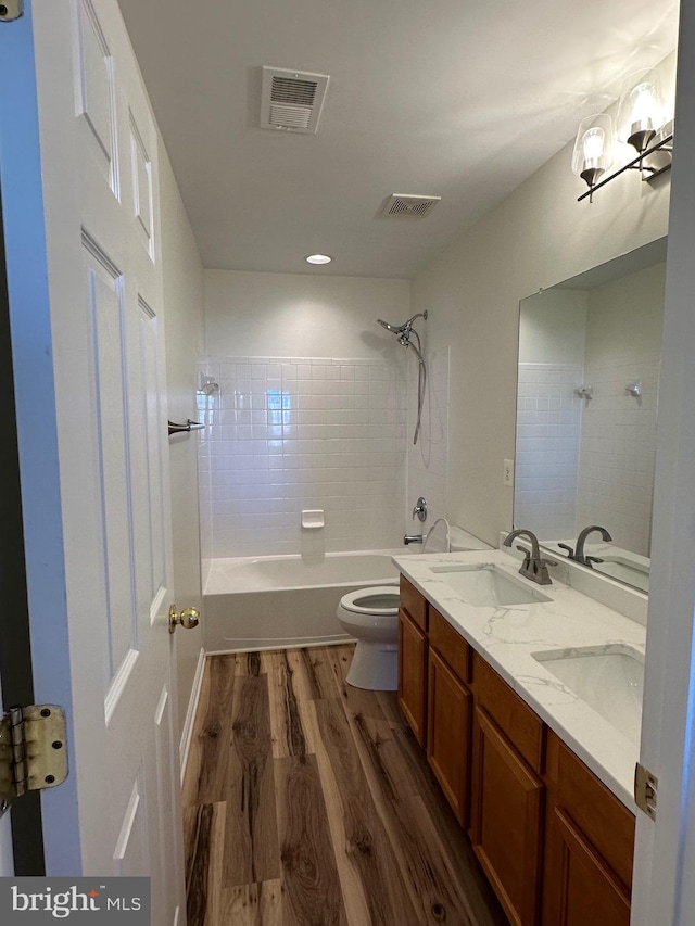 full bathroom featuring vanity, toilet, tiled shower / bath combo, and hardwood / wood-style floors