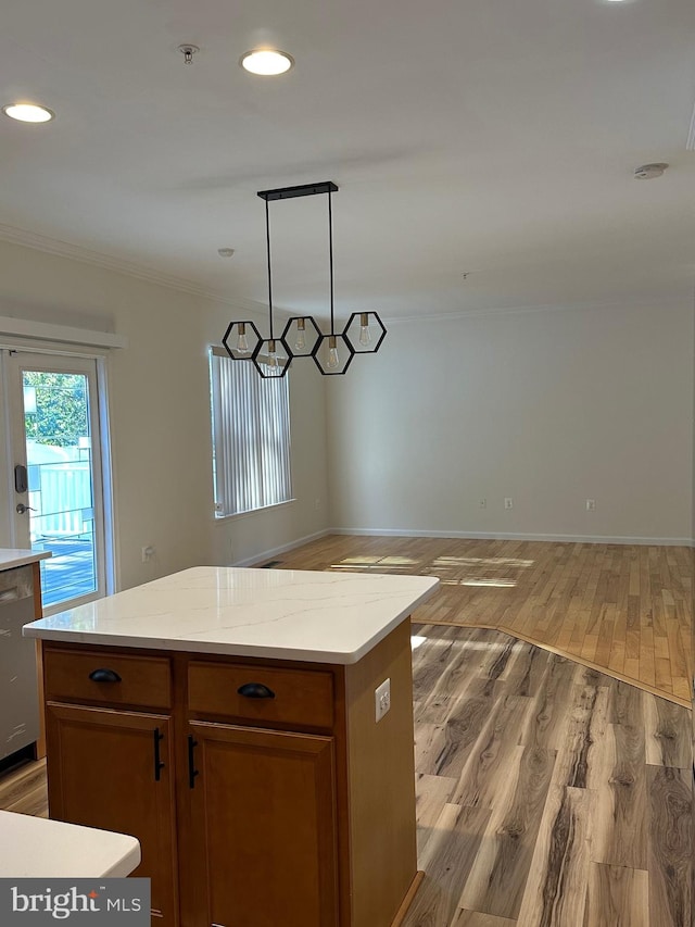 kitchen with dishwasher, light wood-type flooring, a kitchen island, decorative light fixtures, and crown molding