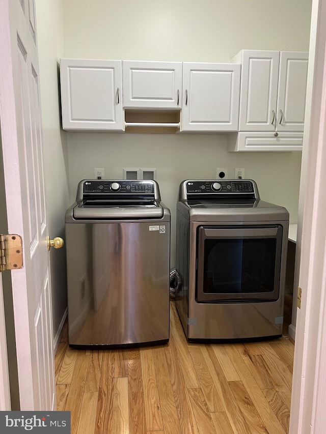 laundry room featuring cabinets, light hardwood / wood-style flooring, and washer and dryer