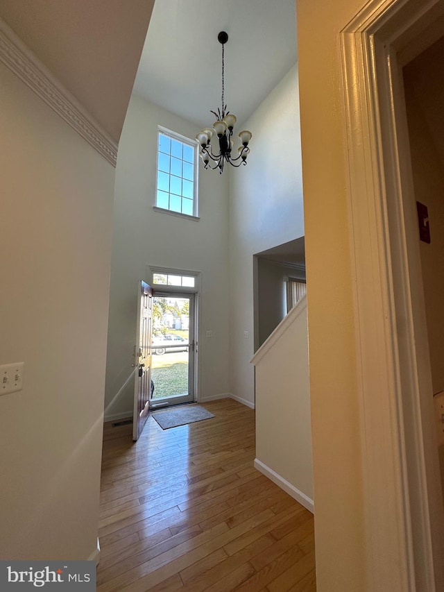 entryway with an inviting chandelier, hardwood / wood-style flooring, and a towering ceiling