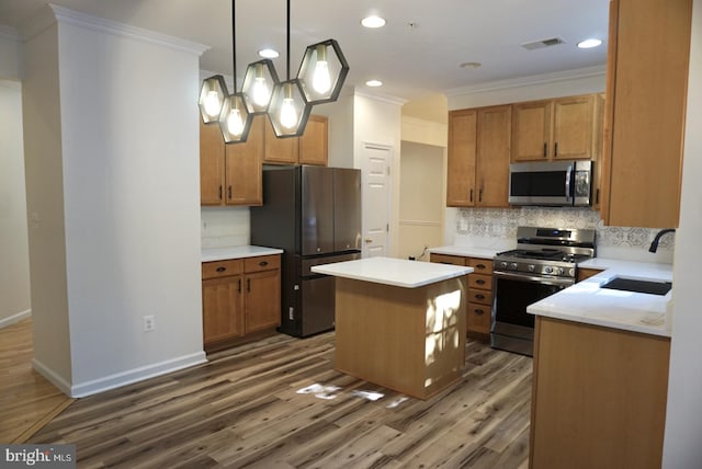 kitchen featuring appliances with stainless steel finishes, sink, a kitchen island, dark wood-type flooring, and ornamental molding