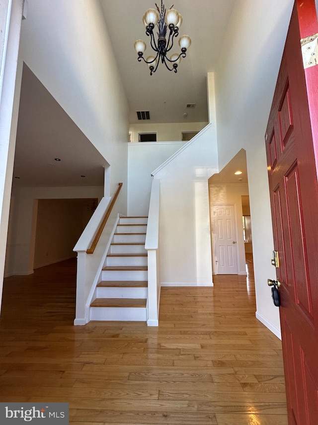 staircase featuring a high ceiling, wood-type flooring, and a chandelier