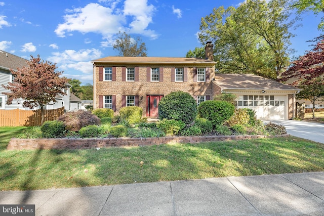 colonial home featuring a front yard and a garage