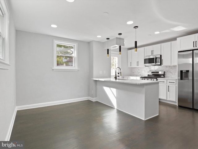 kitchen featuring appliances with stainless steel finishes, kitchen peninsula, decorative light fixtures, and white cabinets