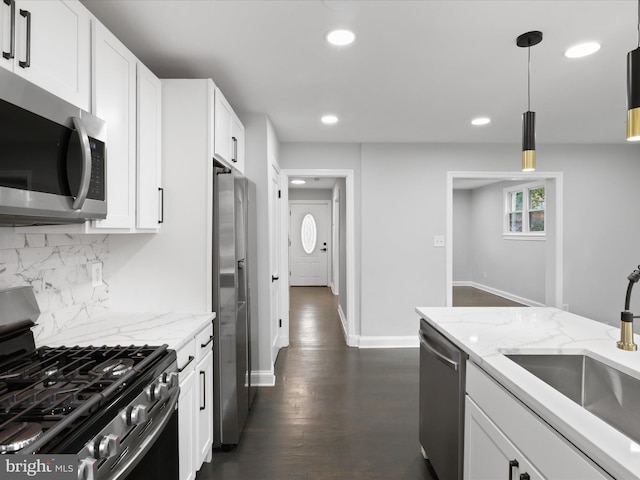 kitchen with stainless steel appliances, decorative light fixtures, white cabinets, light stone counters, and dark hardwood / wood-style flooring