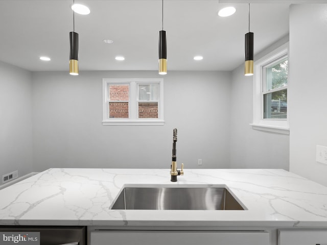 kitchen featuring sink, light stone countertops, and decorative light fixtures