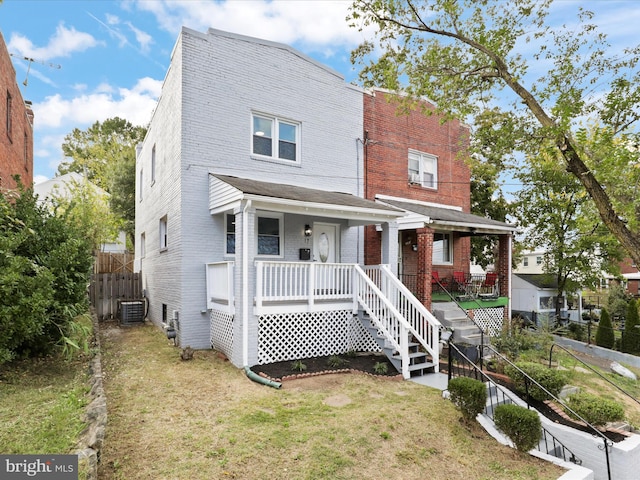 view of front of property featuring a front yard, central AC, and covered porch