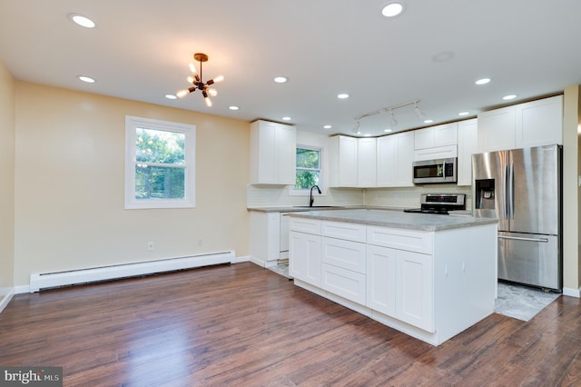 kitchen with stainless steel appliances, white cabinetry, baseboard heating, and sink