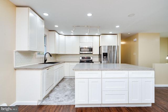 kitchen featuring a center island, backsplash, sink, appliances with stainless steel finishes, and white cabinetry