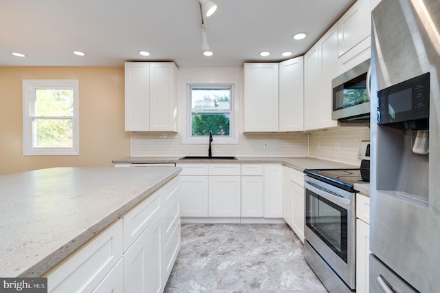 kitchen with white cabinets, light stone countertops, sink, and appliances with stainless steel finishes