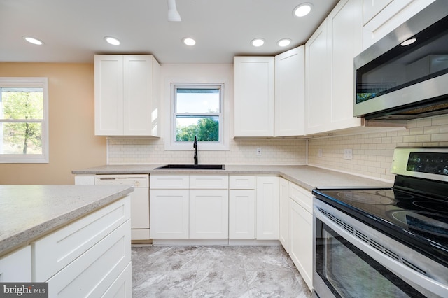 kitchen featuring light stone counters, sink, white cabinets, and appliances with stainless steel finishes