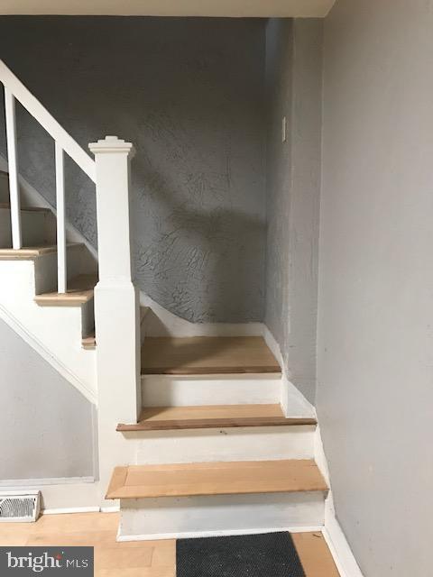 staircase featuring wood finished floors, visible vents, and baseboards