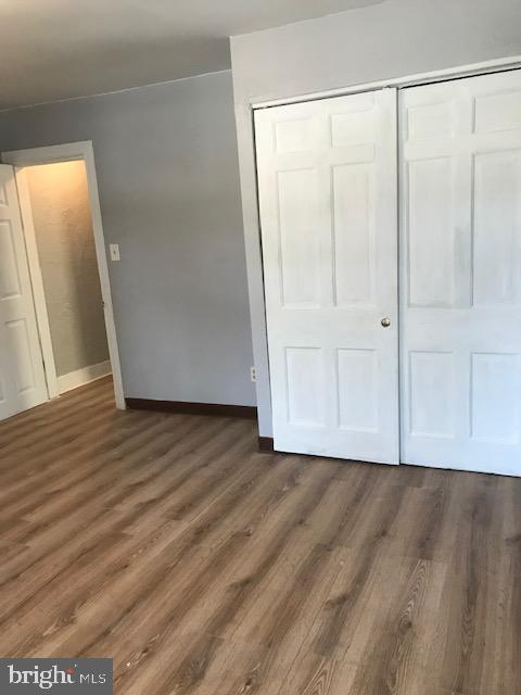 unfurnished bedroom featuring baseboards, wood finished floors, and a closet