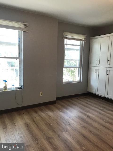 unfurnished bedroom featuring a closet, dark wood-style flooring, baseboards, and multiple windows