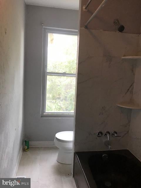 full bathroom featuring toilet, washtub / shower combination, tile patterned floors, and baseboards