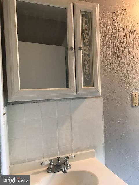 bathroom with a sink and tasteful backsplash