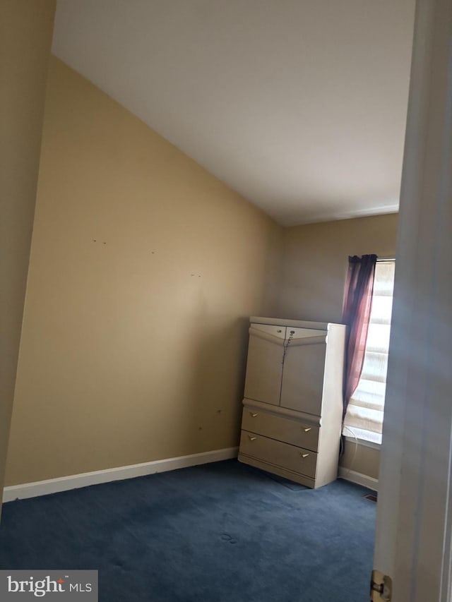 unfurnished bedroom featuring dark carpet and lofted ceiling