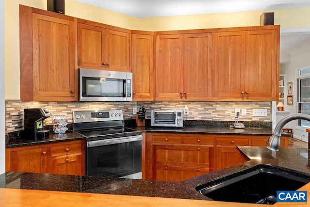 kitchen featuring appliances with stainless steel finishes, sink, dark stone counters, and backsplash