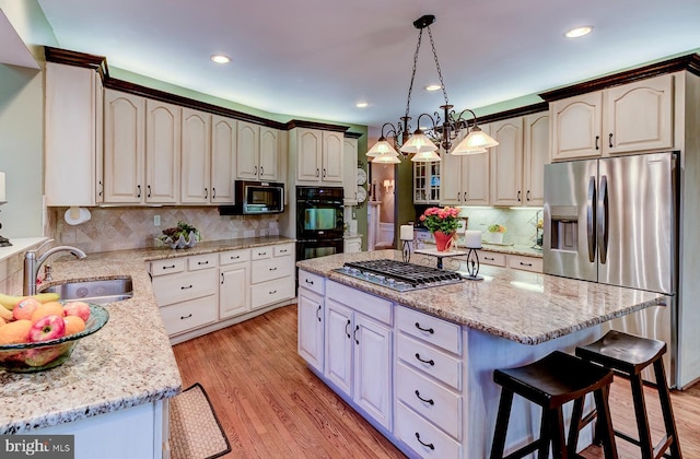 kitchen featuring sink, a center island, light hardwood / wood-style floors, and black appliances