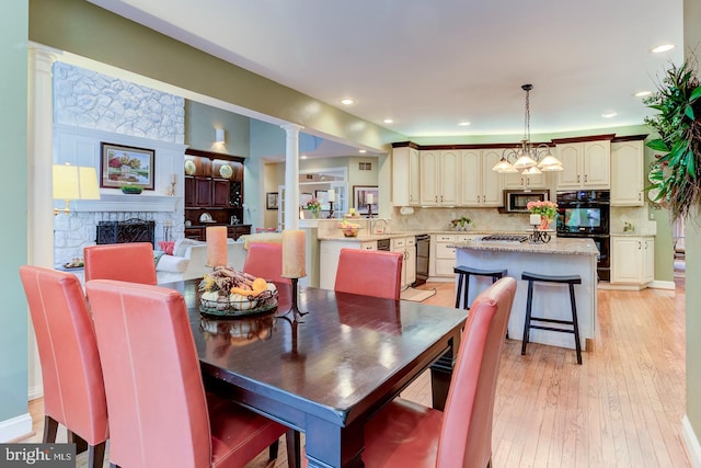 dining area with sink, light hardwood / wood-style flooring, ornate columns, and a fireplace