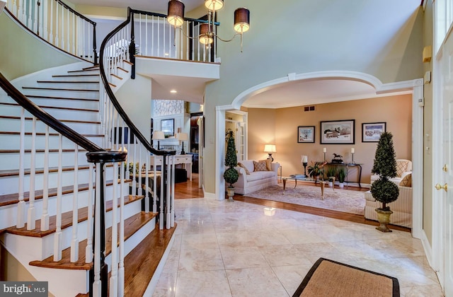 foyer entrance with ornamental molding, a high ceiling, and an inviting chandelier