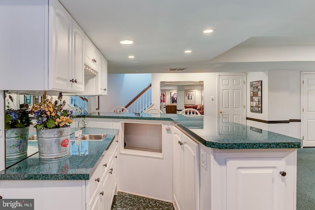 kitchen with white cabinetry, sink, kitchen peninsula, and dark colored carpet