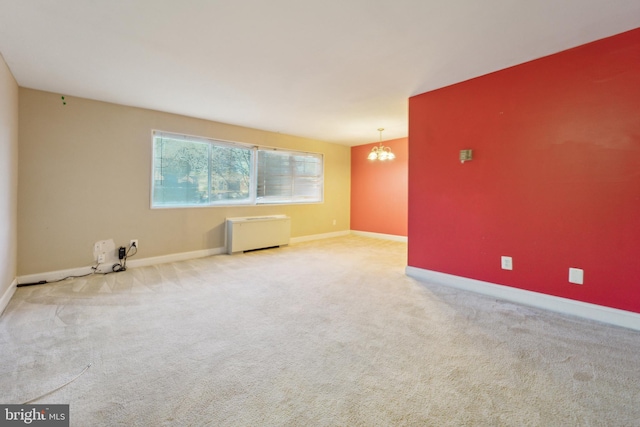 carpeted empty room with radiator and a notable chandelier