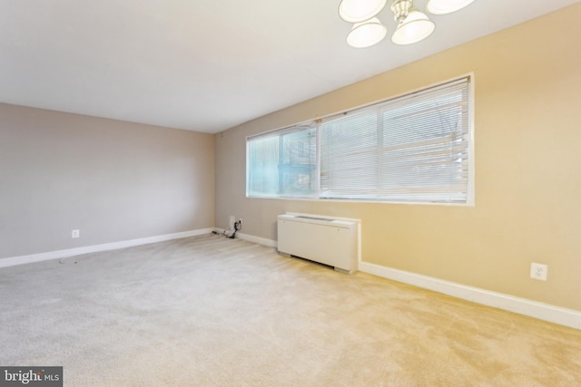 empty room with light colored carpet and an inviting chandelier