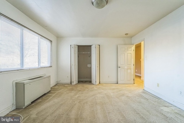 unfurnished bedroom with radiator, a closet, and light colored carpet