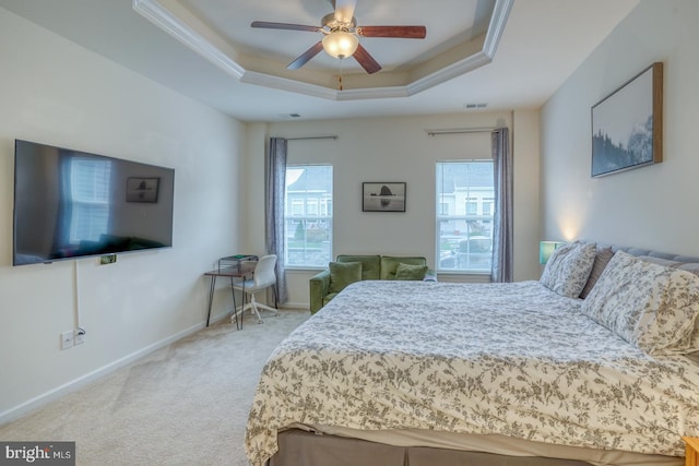 bedroom featuring light carpet, ornamental molding, a tray ceiling, and ceiling fan