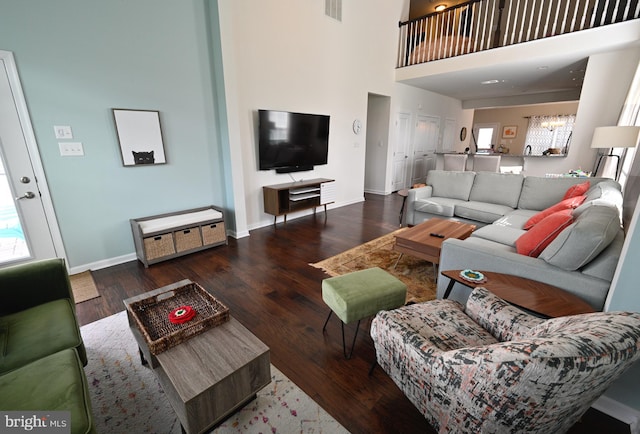 living room with dark wood-type flooring, a towering ceiling, and a chandelier