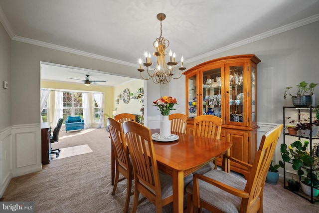 dining space with light carpet, ceiling fan with notable chandelier, and crown molding