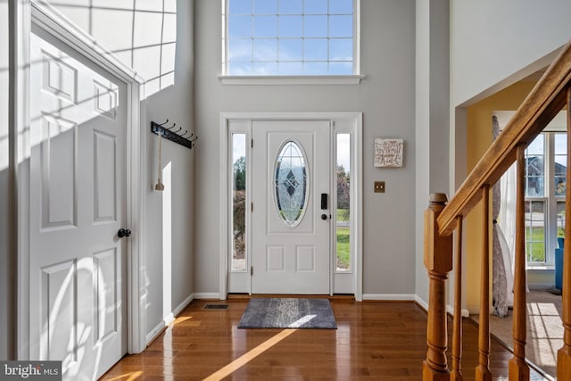 entrance foyer featuring a towering ceiling and dark hardwood / wood-style floors