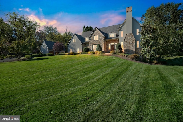 view of front of house with a yard, a chimney, and stone siding